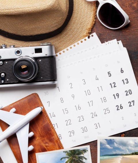 Image of a model airplane, calendar, camera, sun hat and eye glasses on a desk