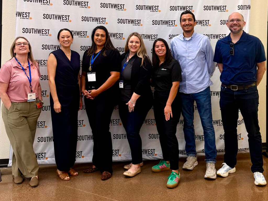 Group photo of six event participants standing in front of a Southwest branding backdrop at a semiconductor or workforce development event. Several participants wear conference badges and business-casual attire.
